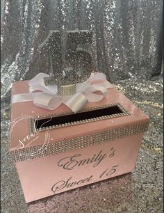 a pink box with a bow on it and the number fifty five in front of silver sequins