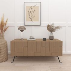 two vases with plants on them are next to a wooden sideboard in a white room