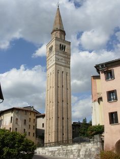 a tall tower with a clock on it's side in the middle of town