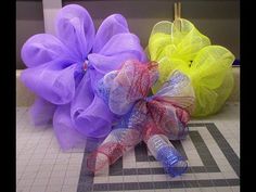 three different colored mesh flowers sitting on top of a tiled floor next to each other