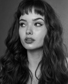 a black and white photo of a woman with long dark hair, wearing a dress