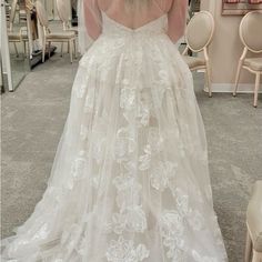 the back of a woman's wedding dress in a room with chairs and mirrors