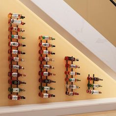 several wine bottles are lined up on the wall next to a stair case in an empty room