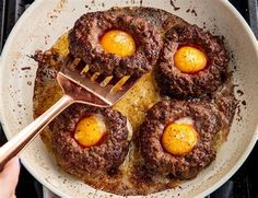 three eggs are being cooked in a frying pan on the stove with a spatula