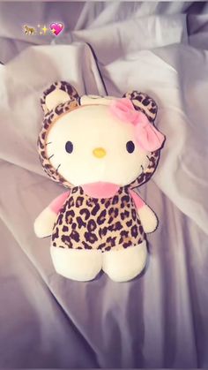 a hello kitty stuffed animal with a pink bow on it's head sitting on a bed