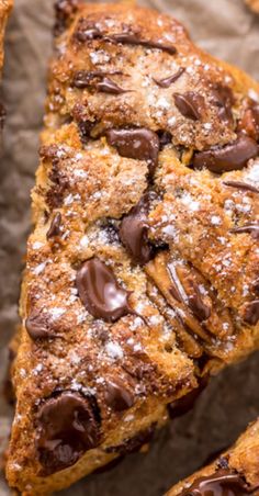 chocolate chip scones sitting on top of a piece of parchment paper with powdered sugar