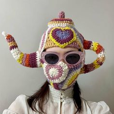 a woman wearing a crocheted hat and sunglasses with an odd shaped object on it's head