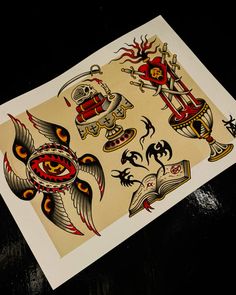 an old school tattoo flash sheet on a black table with some other tattoos in it