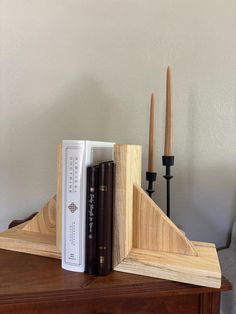 a wooden bookend with two books on it and some candles in the back ground