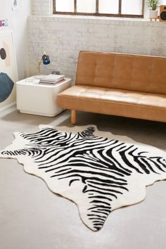 a living room with a brown leather couch and zebra rug