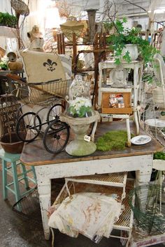 an assortment of furniture and other items in a room with lots of plants on the table