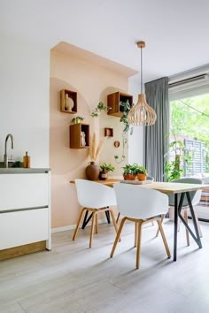 a dining room table and chairs with plants on the wall