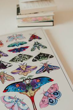 several different colored butterflies are on the table next to each other and one is in front of two books