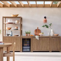 a room filled with lots of wooden furniture and plants on top of shelves next to a table