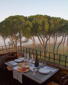 the table is set for two on the balcony overlooking the trees and hills in the distance