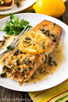 a piece of fish covered in lemon and capers on a plate with a fork