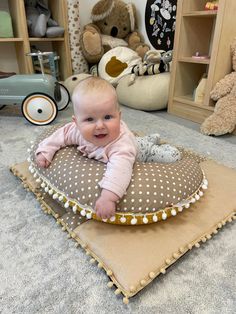 a baby sitting on top of a pillow in the middle of a room