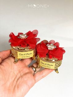 two small red and gold wedding rings with pearls on them are held in the palm of someone's hand