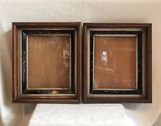 two old wooden framed pictures hanging on the wall next to a white cloth covered towel