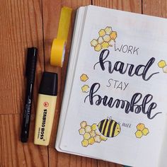 a notebook with the words work hard, stay bumble written on it next to some pens