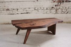 a wooden table sitting on top of a white floor next to a brick wall with exposed beams