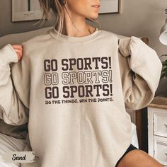 This cozy sweatshirt with "Go Sports" is a must-have Funny Game Day Shirt for any laid-back fan. Perfect as a Sports Mom Shirt or a Funny Girl Sports crewneck, it's a playful choice for soccer, basketball, or football moms who cheer for all the teams with equal enthusiasm. Prefer this design on a T-Shirt? Visit this link:  Everything You Need to Know: 🧥 Sweatshirt Brand Gildan | Unisex Adult Sizing | 50% Cotton, 50% Polyester ⏳🚚 Production & Shipping All items are made-to-order. They will ship within 1-5 business days from one of our printing partners, shipping usually takes between 2-5 business days after the item is shipped. Please allow sufficient time for production and shipping.  Important: Please double-check your shipping address before checking out. A fee will apply if an order n Sporty Sweatshirt For Sports Season, Athletic Heather Sweatshirt For Sports Fans, Athletic Heather Sportswear Sweatshirt For Sports Season, Sporty Slogan Activewear For Sports, Sporty Activewear With Slogan For Sports, Sporty Relaxed Fit Sweatshirt For Sports Events, Athletic Heather Team Spirit Sweatshirt For Sports, Sporty Sweatshirt For Football Season Sports Events, Winter Sports T-shirt With Letter Print