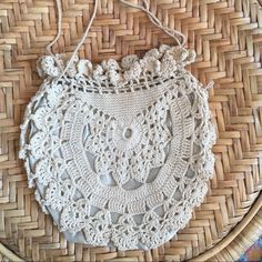 a white crocheted purse sitting on top of a wicker basket