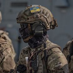 the soldier is wearing a helmet and goggles on his head while standing in front of other soldiers