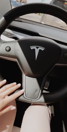 a woman driving a car with her hand on the steering wheel and hands on the dashboard