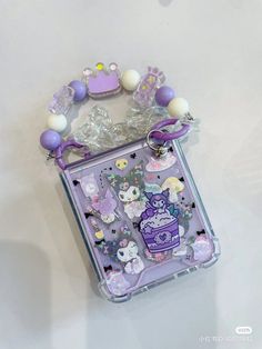 a purple and white cell phone case sitting on top of a table next to some beads