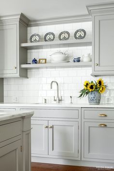 a kitchen with white cabinets and sunflowers on the counter top in front of it