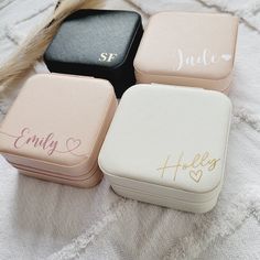 four personalized jewelry boxes sitting on top of a white blanket with long hair in the background