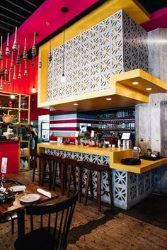 the interior of a restaurant with yellow and red walls, wooden tables and stools