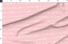 a pink fabric with white writing on it and a ruler next to it that shows the length