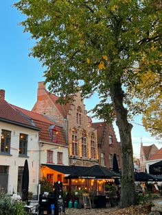 an outdoor market with tables and umbrellas in front of buildings