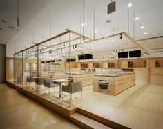 an empty room with wooden floors and lots of glass cases on the wall, in front of a kitchen