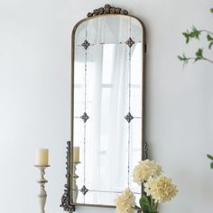 a white dresser topped with a vase filled with flowers and a mirror on top of it