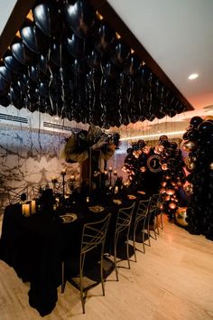 a room filled with lots of black balloons and tables covered in black tablecloths