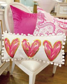 pink and gold heart pillows on a white chair