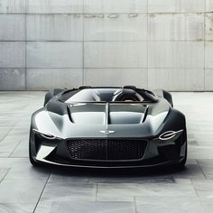 an electric sports car is parked in front of a concrete wall and cement flooring