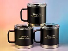 four black coffee mugs with words on them sitting next to each other in front of a colorful background