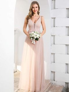 a woman in a long pink dress is posing for the camera while holding a bouquet