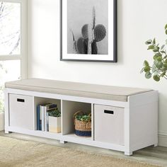 a white bench with two bins underneath it and a plant on the wall next to it