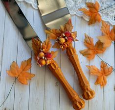 two wooden utensils decorated with flowers and leaves next to a knife on a lace doily