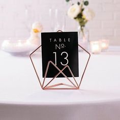 a table number is placed on top of a white table cloth with candles in the background