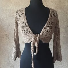 a mannequin wearing a crocheted sweater with a tie around the neck