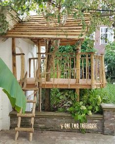 a tree house made out of branches and wooden ladders in the middle of a garden