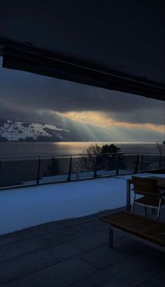 the sun is shining down on some snow covered hills and mountains in the distance, as seen from an outdoor dining area