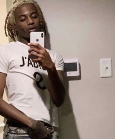 a man with dreadlocks taking a selfie in front of a bathroom mirror