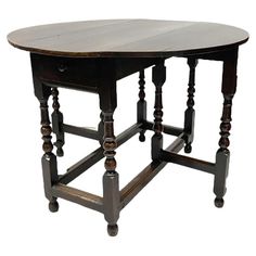 an old wooden table with turned legs and a round top on one end, against a white background